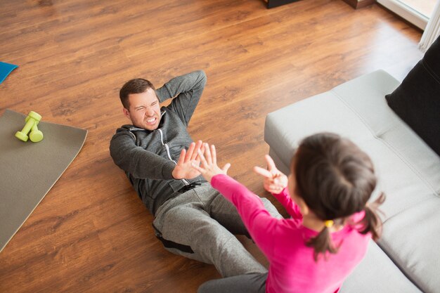父と娘は家で腹筋トレーニングをしています アパートでのトレーニング 居間でのスポーツトレーニング プレミアム写真