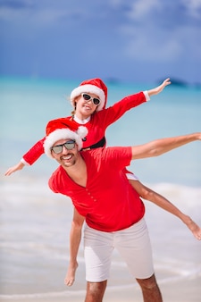 산타 모자에 아버지와 딸 열 대 해변에서 즐거운 시간을