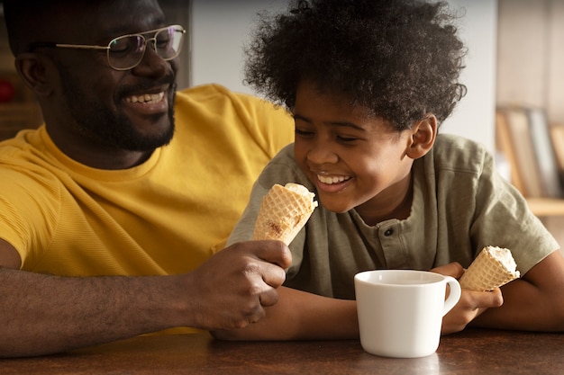 Бесплатное фото Отец и сын вместе едят мороженое на кухне