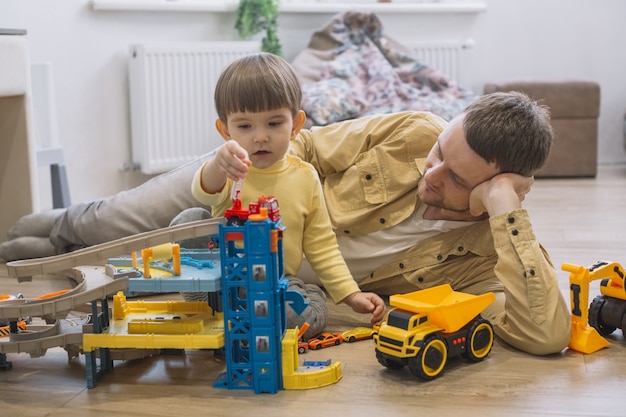 Бесплатное фото Отец и сын играют с игрушечными машинками