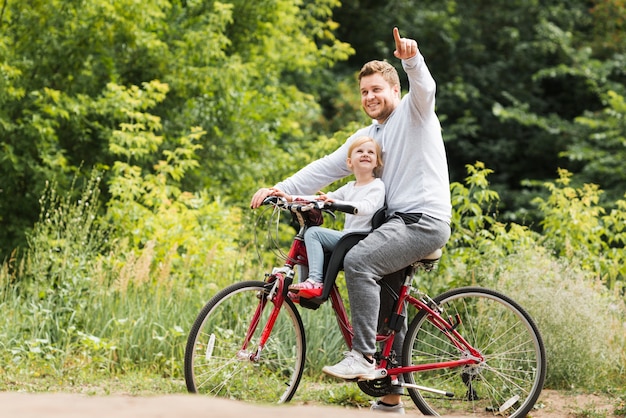 Father on bicycle pointing for daughter