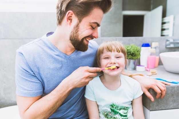 Father brushing teeth of daughter