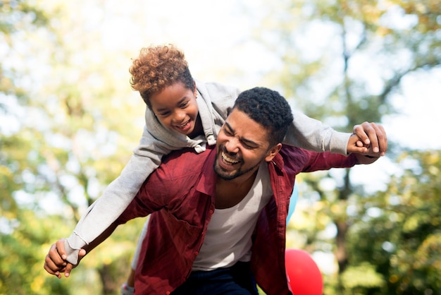 Father carrying daughter on his back with arms spread