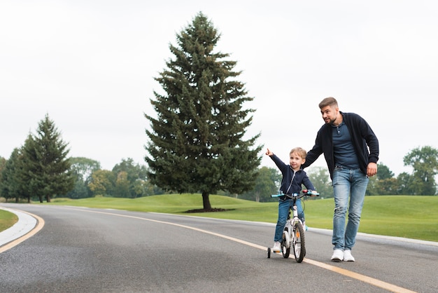 Father and child playing in park with bike