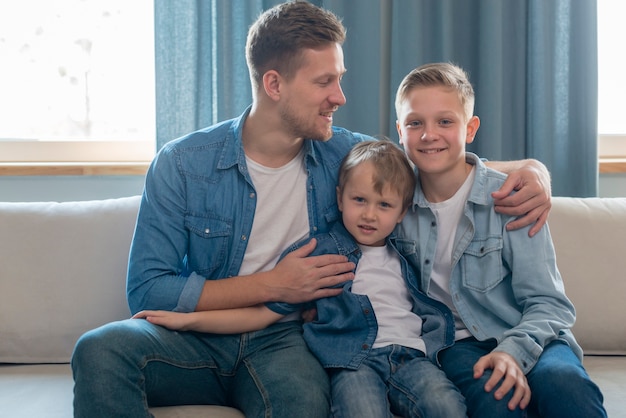 Father and cute brothers sitting on the couch