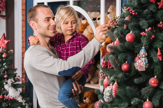 Father and daughter in front of decorative christmas tree