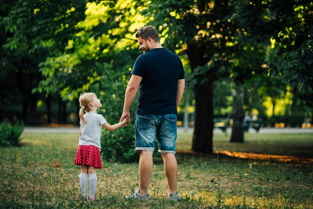 Father and daughter holding hands from behind