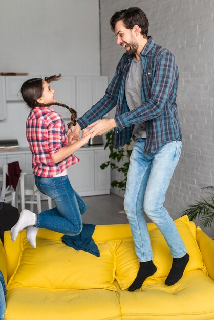 Father and daughter jumping on sofa