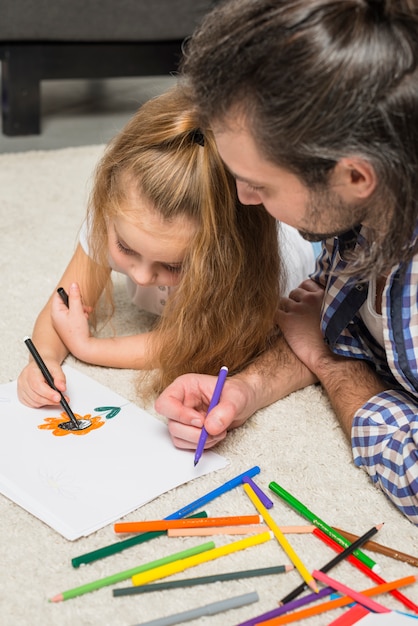 Father and daughter painting on the floor