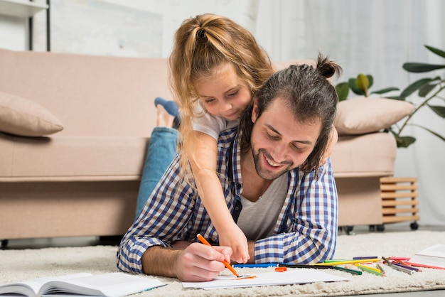 Father and daughter painting on the floor