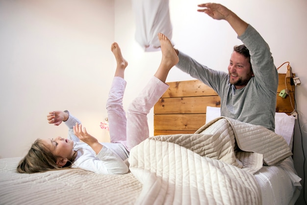 Отец и дочь играют в постели