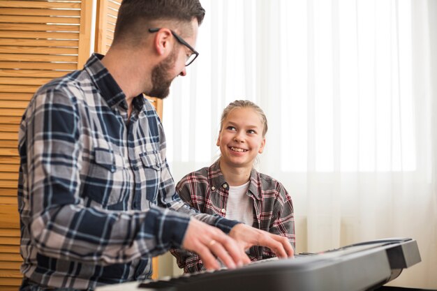 Free photo father and daughter playing on the piano