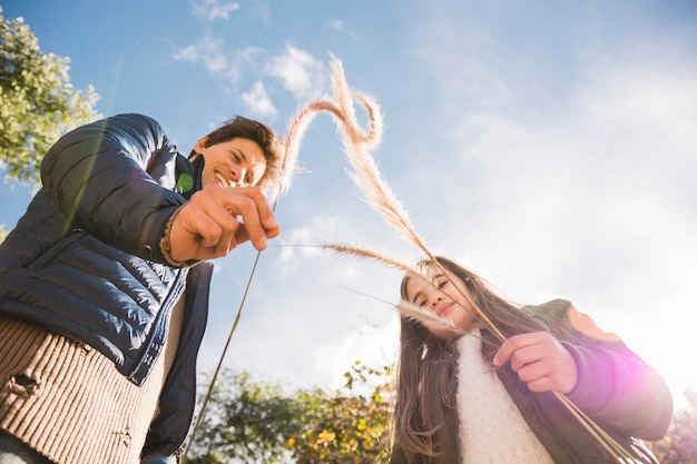 Free photo father and daughter playing with reeds in park