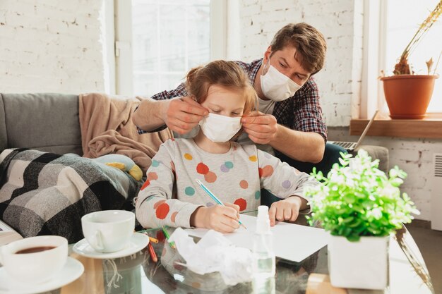 Father and daughter in protective masks and gloves isolated at home