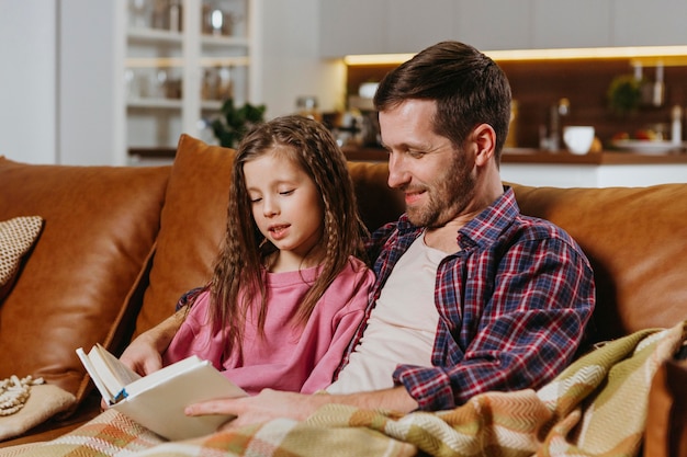 Free photo father and daughter reading book at home