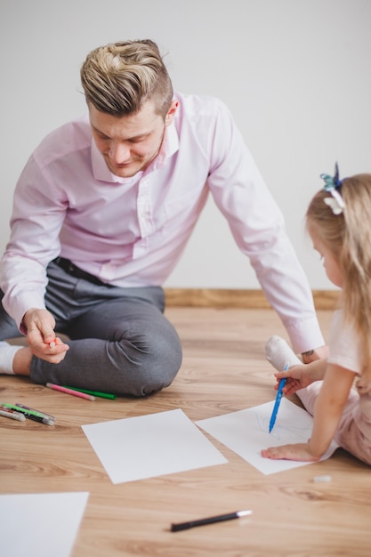 Father and daughter sitting on the floor drawing