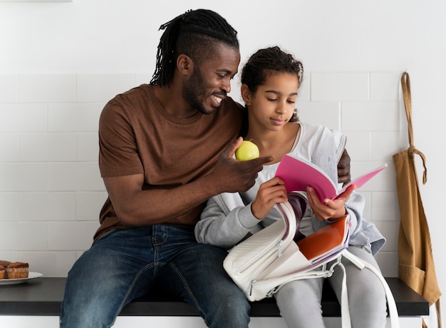 Free photo father and daughter sitting on a kitchen counter