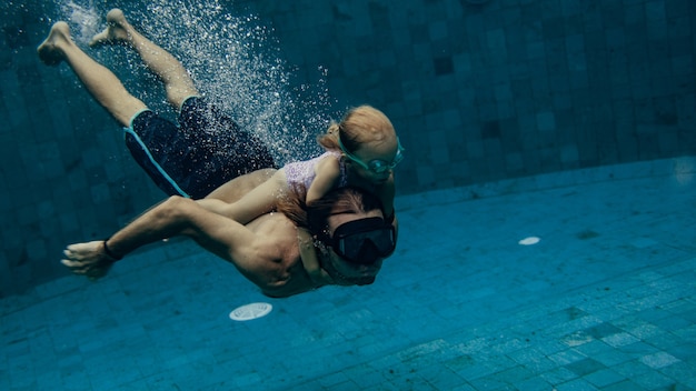 Father and daughter swimming together in pool