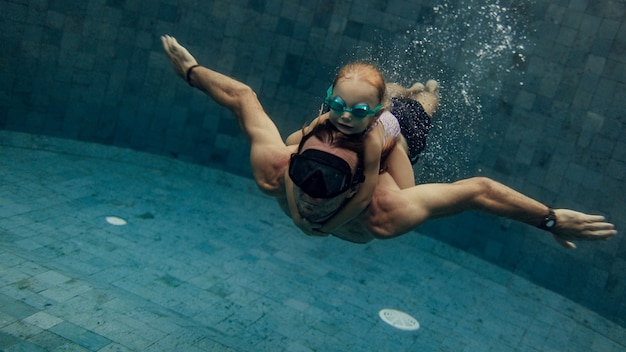 Отец и дочь вместе плавают в бассейне