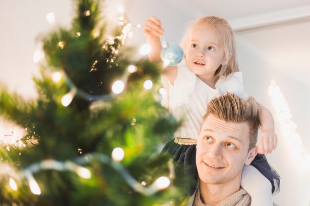 Father and daughter touching illuminated christmas tree