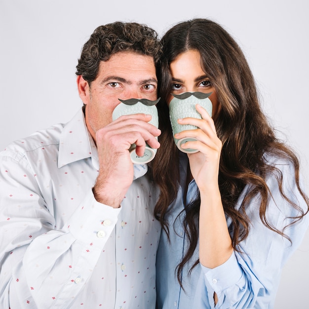 Free photo father and daughter with cups looking at camera