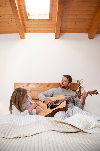 Father and daughter with musical instruments in bed
