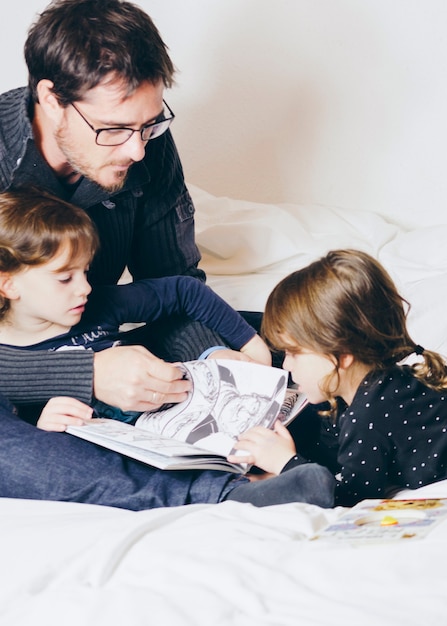 Father and daughters reading comic book