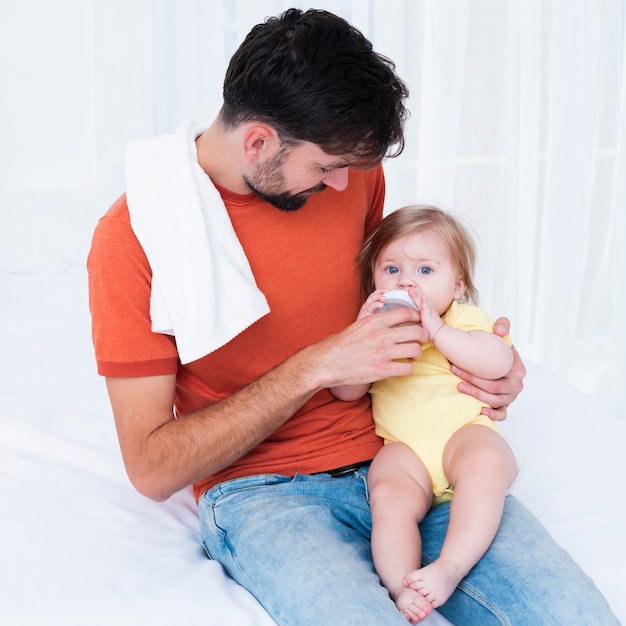 Father feeding baby on bed