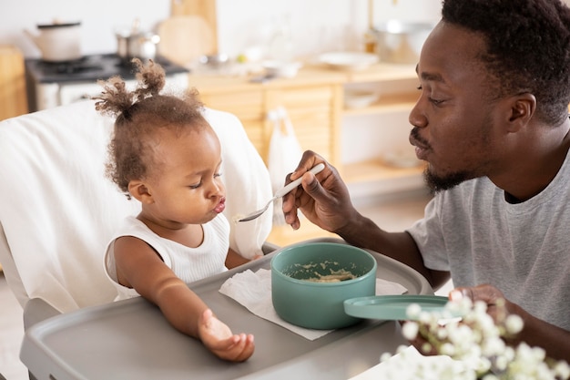 Father feeding his little baby girl in the kitchen