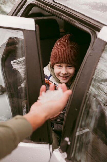 Father giving son snow while on a road trip together