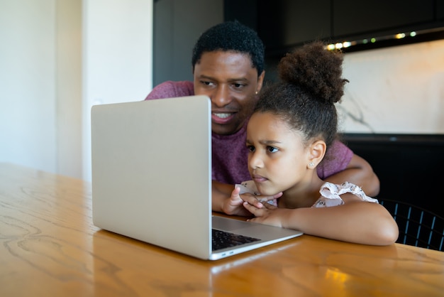 Отец помогает и поддерживает свою дочь в онлайн-школе, оставаясь дома