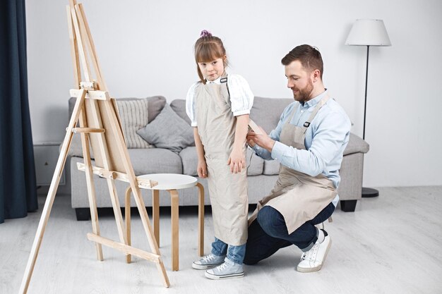 Father helping his daughter with Down syndrome to wear an apron