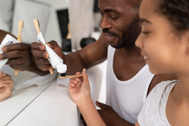 Отец помогает дочери с зубной пастой