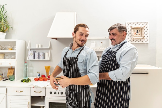 Foto gratuita figlio d'aiuto del padre con il grembiule da cucina