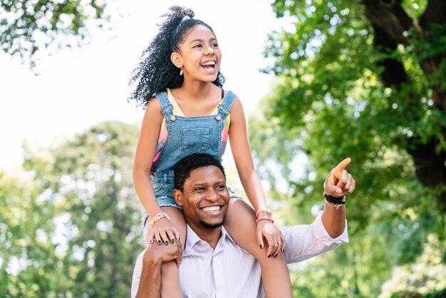 A father and his daughter having fun and spending good time together while walking outdoors on the street.