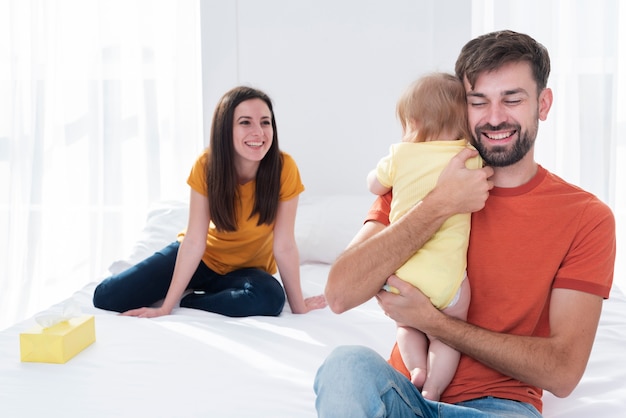 Free photo father holding baby in bed