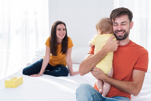 Father holding baby in bed