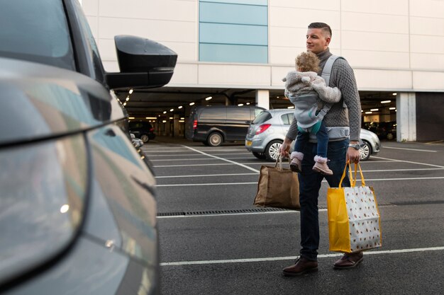 Father holding baby in carrier full shot