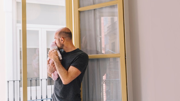 Father holding baby in front of window