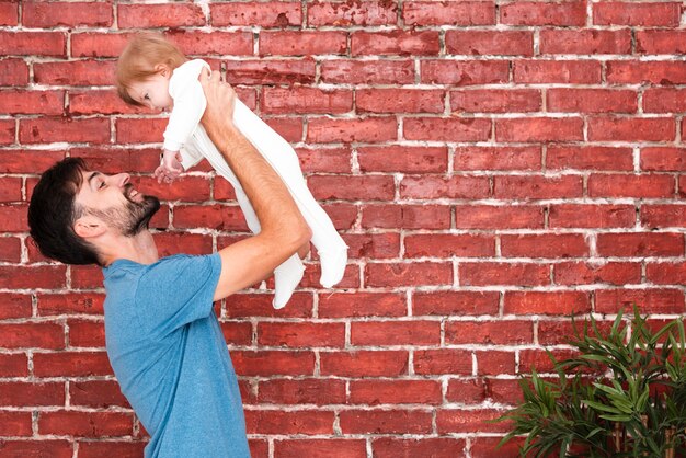 Father holding baby with corner plant