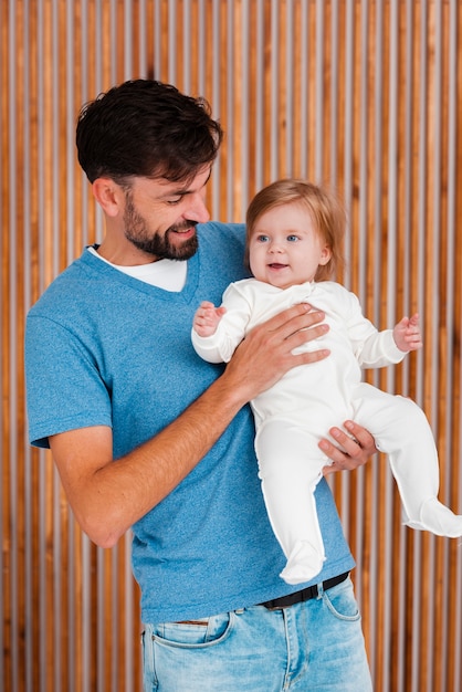 Father holding baby with wooden background