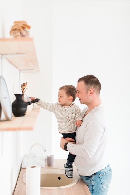 Father holding child while in the kitchen