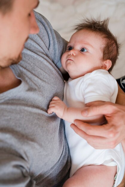 Father holding cute baby on bed