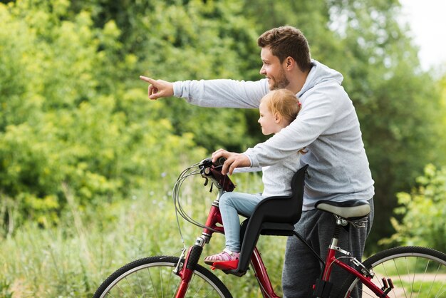 Отец держит дочь на велосипеде