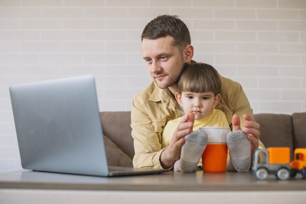 Free photo father holding son and working from home