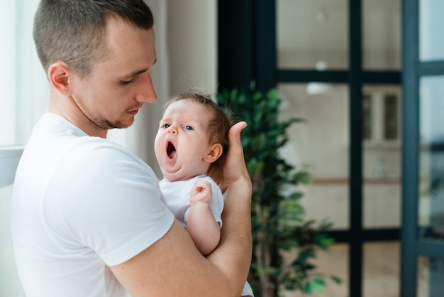 Father hugging yawning baby