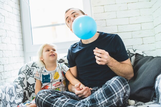 Отец надувать воздушный шар для своей дочери