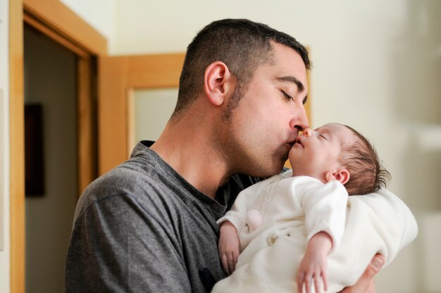 彼の新生児の女の子にキスする父。