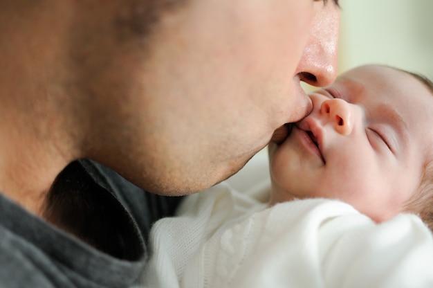 Father kissing his newborn baby girl. 