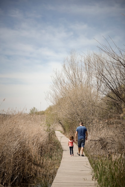 Father and little daughter walking on a path of wooden boards in a wetland, Granada, Andalusia